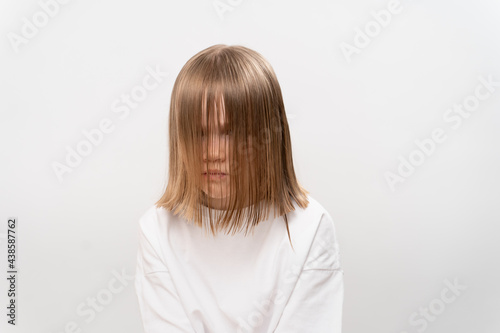 sad little girl with hair covers the face on a white background.