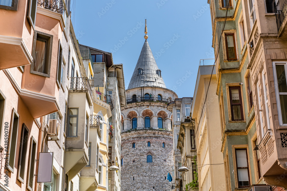 Obraz premium Famous tourist place Galata tower seems between old traditional buildings. Empty street, no people. Istanbul during coronavirus lockdown.