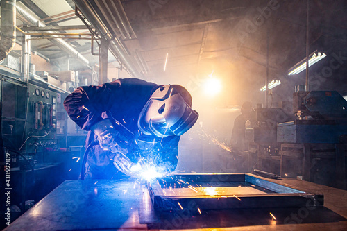 Two handymen welding and grinding metal at workshop photo