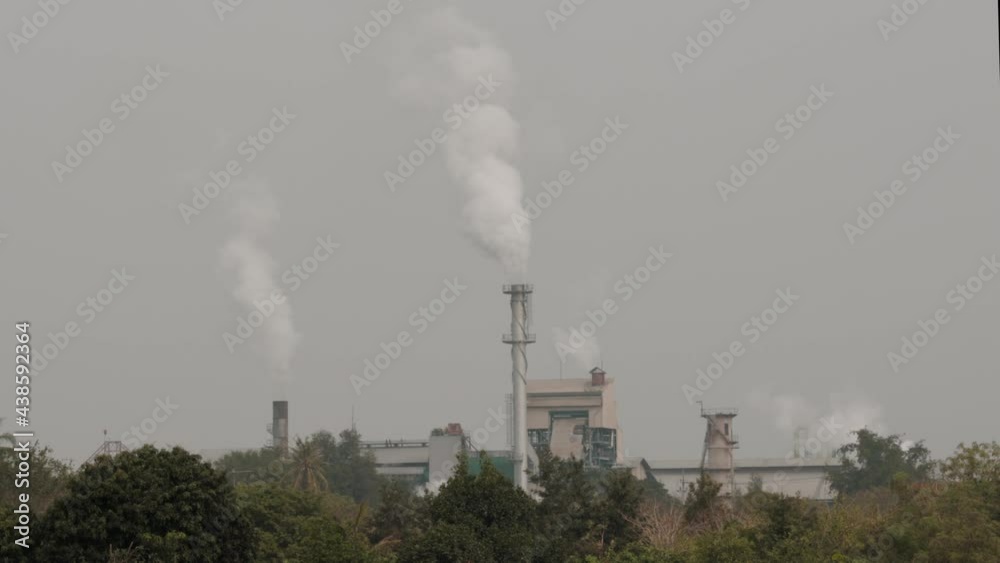 The industrial factory in the middle of the forest is emitting fumes of pollution through the pipe. The industrial factory in the middle of the forest is emitting fumes of pollution through the pipe.