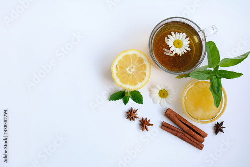 Cup of tea with chamomile, lemon, cinnamon sticks, yata and honey on a white background, top view. Copy space
