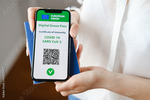 Unrecognized woman holding smartphone with digital green pass and QR code on the screen. Health passport or certificate of immunity. Traveling without restrictions. Vaccinated person