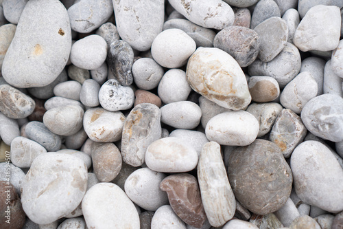White and gray stones on the beach. Beach pebbles. Beach stones background. Top view. Beach rocks background