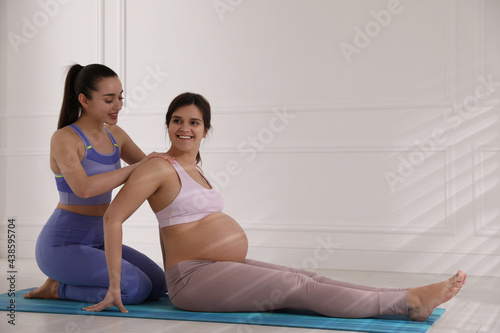 Trainer working with pregnant woman in gym. Preparation for child birth