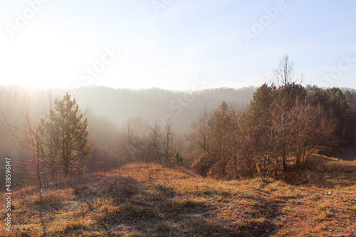 .A glade in the mountains, illuminated by the rays of the setting sun. Fog.