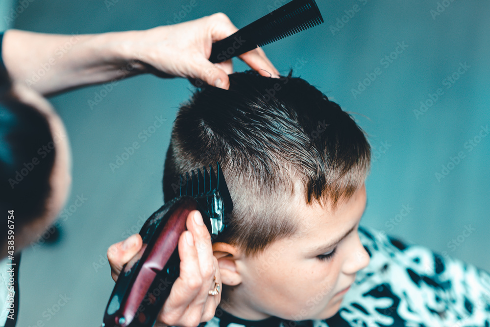 Fototapeta premium Cute kid have hair cut,professional barber doing haircut. Hairdress for children. side view portrait barbershop.Toned