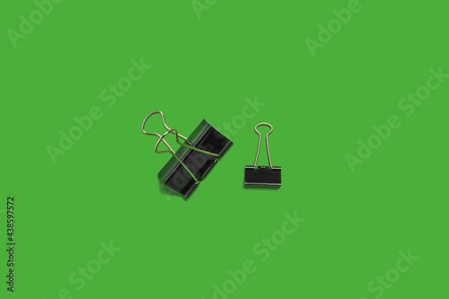 small and big paper clips on a green surface