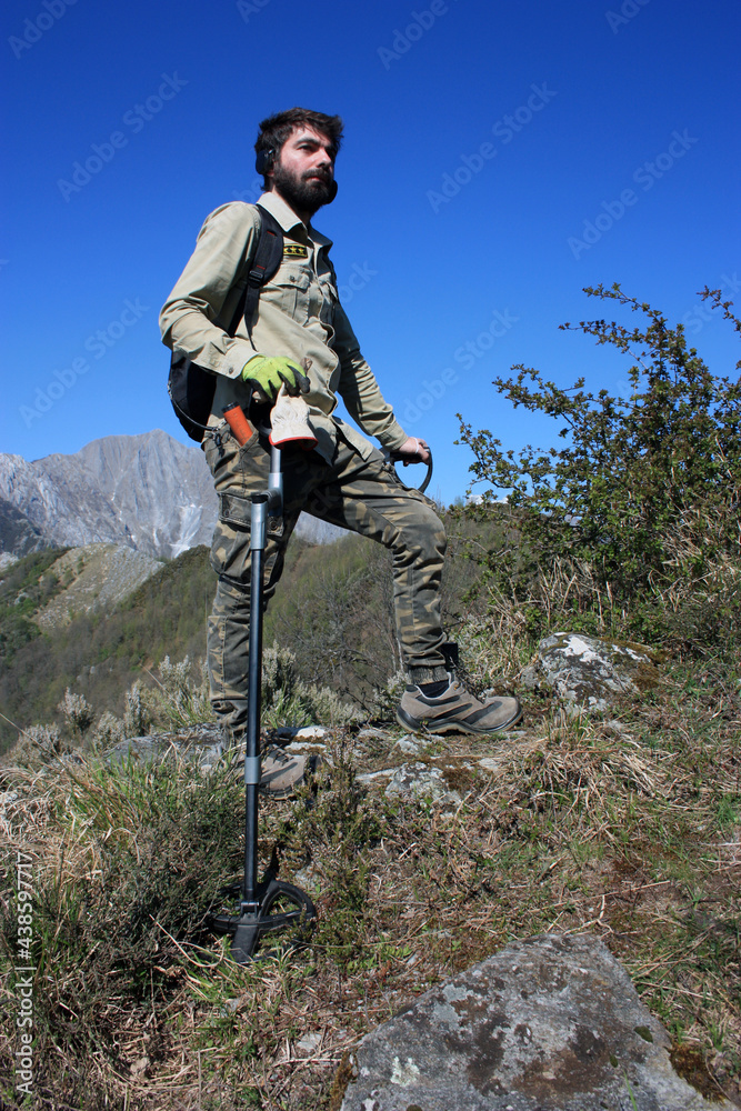 in search of buried treasures with the metal detector in a steep path between peak of the rocky and green mountains in search of buried treasures with the metal detector in a steep path between peak of the rocky and green mountains
