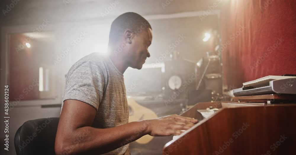 Black man playing synthesizer in recording studio