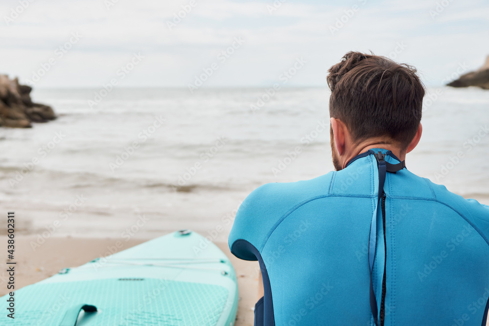 Fototapeta premium Man looking at the sea with paddle board