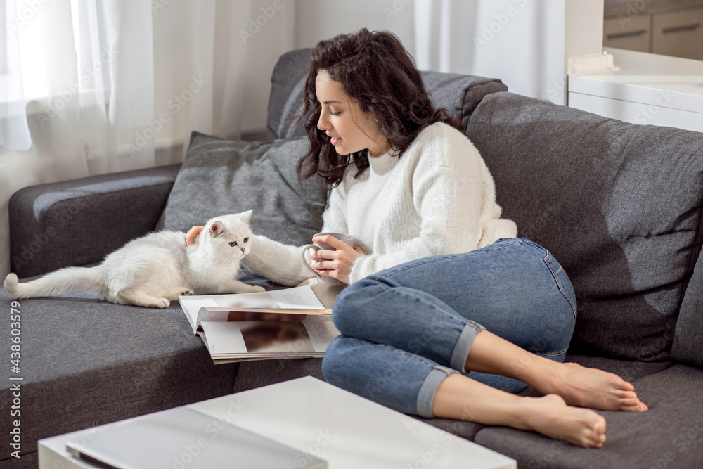 Young woman resting at home with her cat and looking relaxed