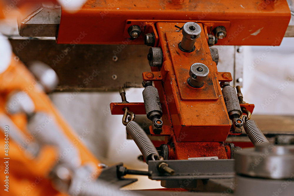 selective focus photo of fragment of print screening apparatus. serigraphy production. printing images on t-shirts by silkscreen method in a design studio selective focus photo of fragment of print screening apparatus. serigraphy production. printing images on t-shirts by silkscreen method in a design studio