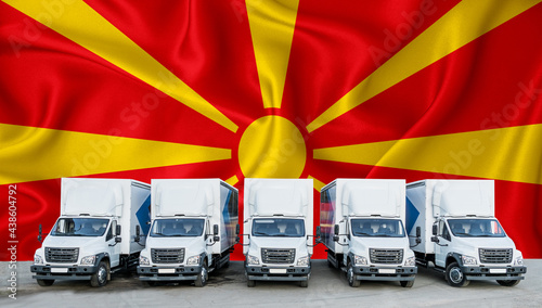 Macedonia flag in the background. Five new white trucks are parked in the parking lot. Truck, transport, freight transport. Freight and logistics concept