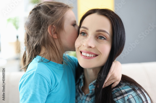 Little girl whispers secret in mom ear