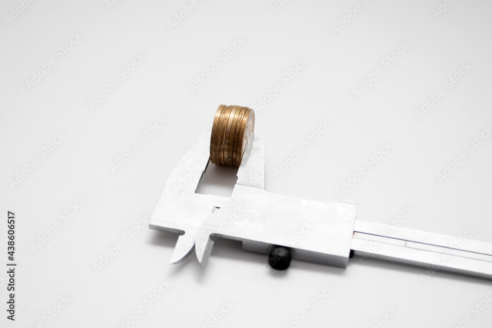 Coins in Caliper. Economic and financial concept Coins in Caliper. Economic and financial concept