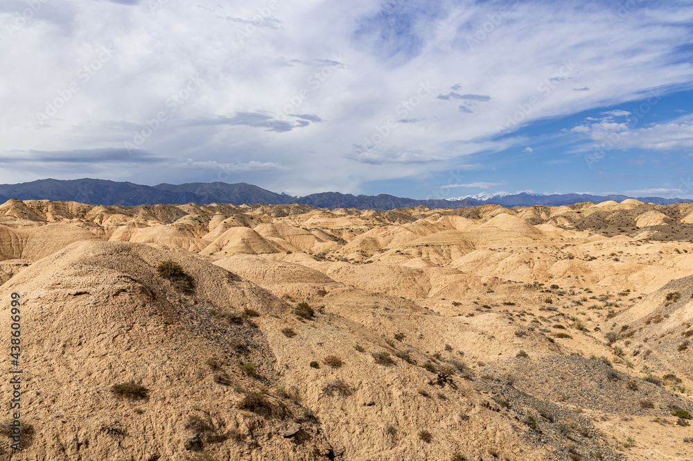 dried sand dunes against the backdrop of mountains and blue sky