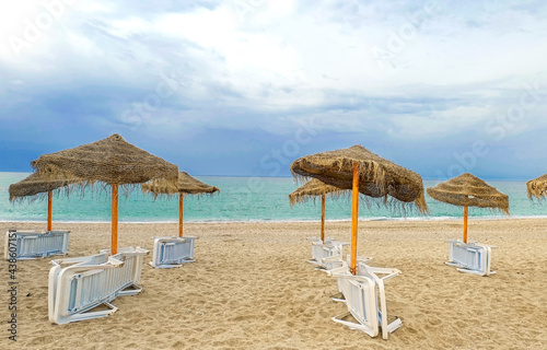 white plastic sun loungers  sun umbrellas on the beach.
