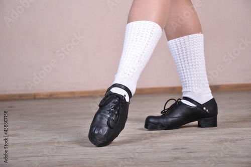 Close-up of female legs in black leather shoes dancing national Irish dances.