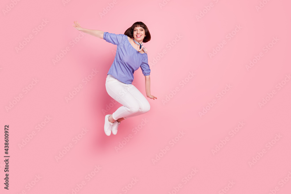 Full length body size photo woman jumping high playful smiling overjoyed isolated pastel pink color background Full length body size photo woman jumping high playful smiling overjoyed isolated pastel pink color background