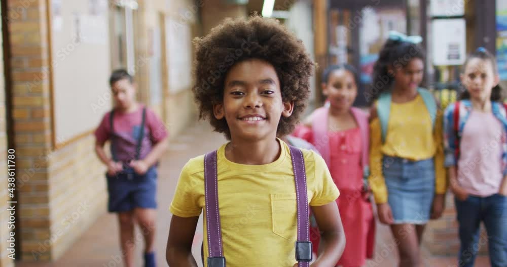 Portrait of happy african american schoolboy standing in corridor looking at camera