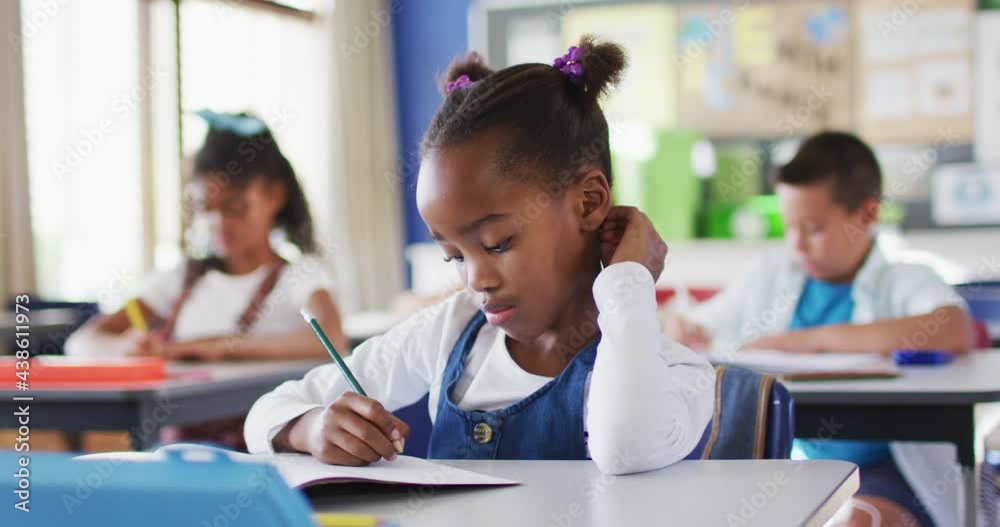 Portrait of african american schoolgirl sitting in classroom, making notes Portrait of african american schoolgirl sitting in classroom, making notes