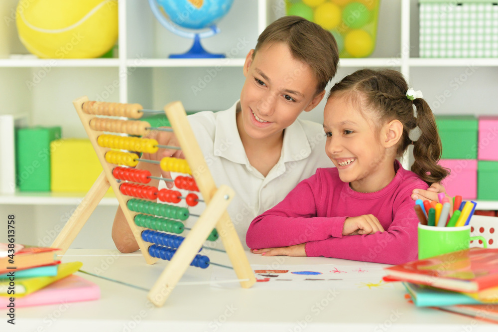 Fototapeta premium Boy and girl sitting at table and counting on abacus