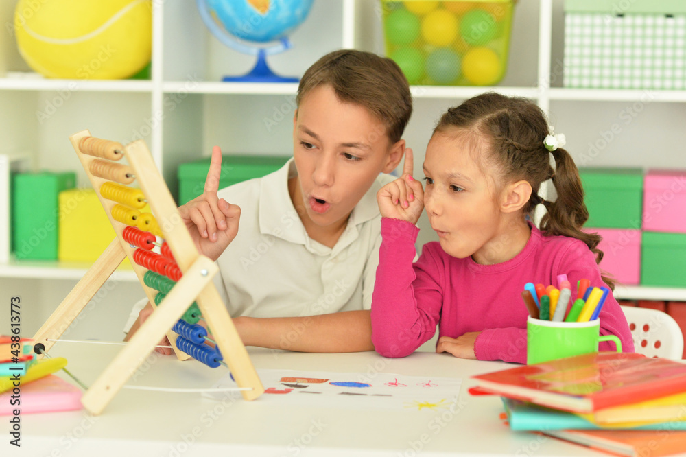 Fototapeta premium Boy and girl sitting at table and counting on abacus