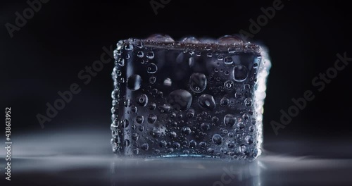 Closeup ice cubes rotating on dark background.