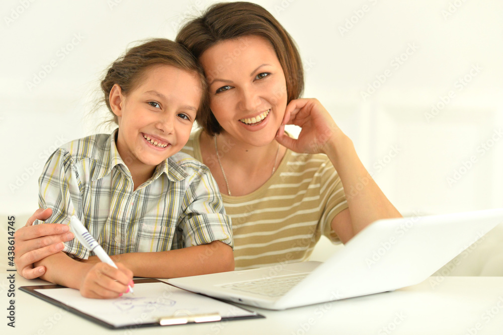 Cute girl and mother using laptop at home at desk Cute girl and mother using laptop at home at desk