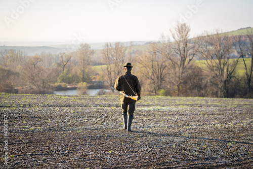 Scenic view of hunter waiting for a prey. Gamekeeper walks over field.
