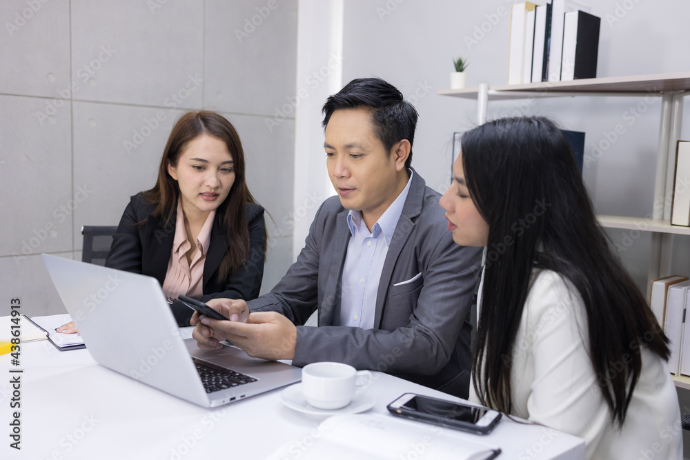 Motivated middle-aged Asian businessman and two young businesswomen happily exchanged ideas for business plans, enjoying working together at the office. leadership workplace. Motivated middle-aged Asian businessman and two young businesswomen happily exchanged ideas for business plans, enjoying working together at the office. leadership workplace.