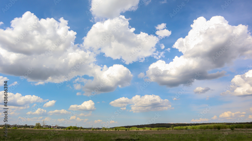 A field with a clear blue sky filled with white clouds in the background in bright sunny summer weather without wind or rain. A field with a clear blue sky filled with white clouds in the background in bright sunny summer weather without wind or rain.