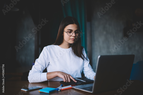 Serious woman surfing laptop in workplace