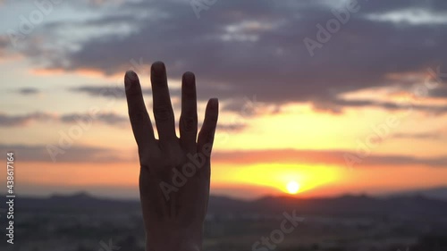 Closeup 4k video of isolated on sunset landscape female hand hand counting from 0 to 5. Woman shows fist first, then one, two, three, four, five fingers. Hand gesturing thumb up sign. Math concept photo