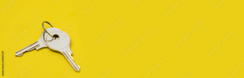 Small keys to a new apartment on a yellow background with an empty space Small keys to a new apartment on a yellow background with an empty space