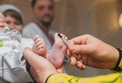 The priest performs the ceremony of anointing the baby photo