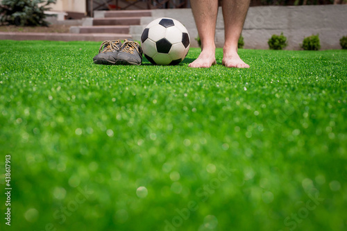 Legs of unrecognizable barefoot football player against artificial grass. Soccer ball  street football shoes. Copy space.