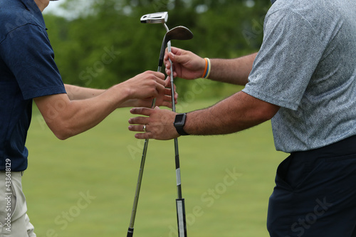 Caddy hands a putter to a golfer.