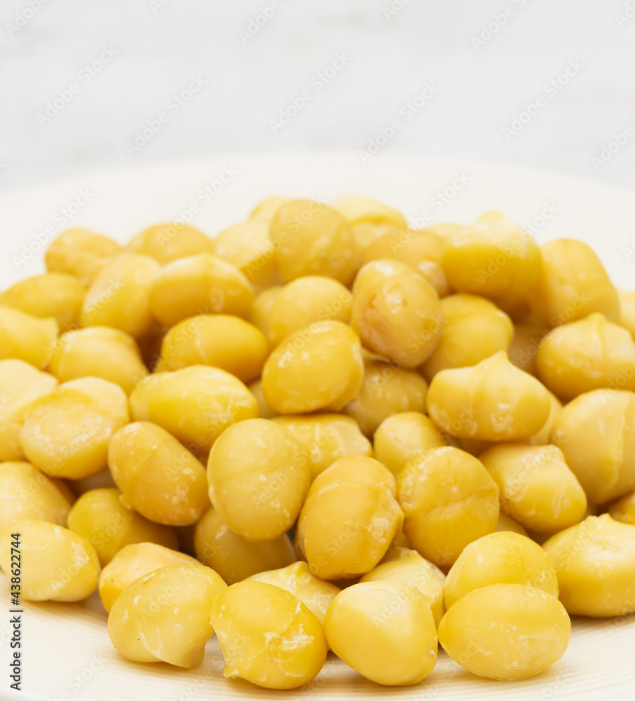 Close up raw macadamia seeds on plate on stone background with copy space