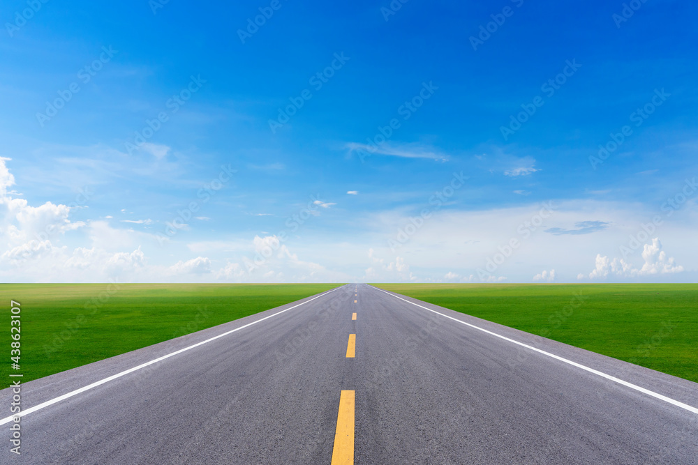 long road into grass field and blue sky long road into grass field and blue sky