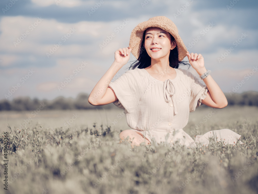 Cheerful asian young woman wear vintage dress with retro hat on the field at sunset