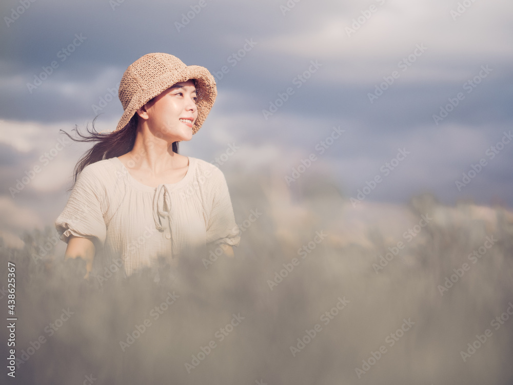 Cheerful asian young woman wear vintage dress with retro hat on the field at sunset