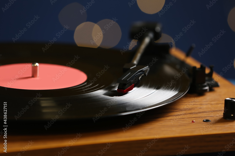 Obraz premium Vinyl record on turntable against blurred lights, closeup