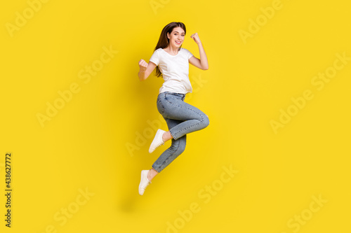 Full length body size view of attractive cheerful girl jumping rejoicing isolated over bright yellow color background
