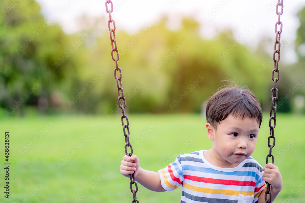 Little asian boy on a swing in summer garden on warm and sunny day outdoors., Background. Copy space.
