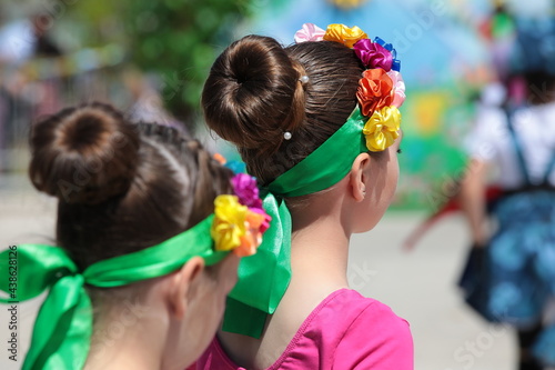 Portrait of a teenage girl dancer performing at a children's party together with her peers.The beautiful head of the brunette is decorated with a bright satin ribbon.Creative holiday background