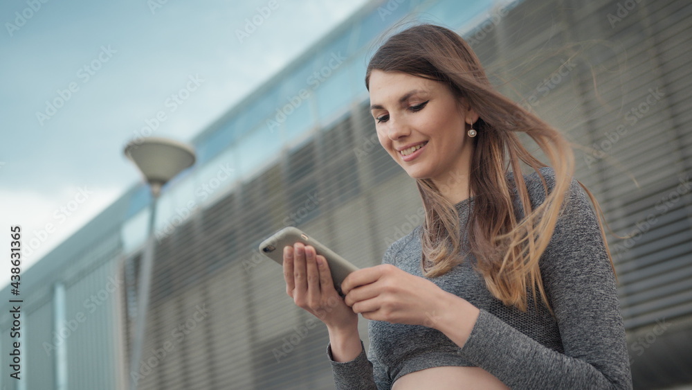 Fitness, sport and technology concept - happy smiling woman running outdoors. Close-up Of A Young Beautiful Sports Fitness Girl Holding A Smartphone In The Hands. Phone conversation during training
