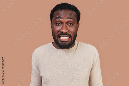Frustrated young African man in casual clothing making a face and looking at camera