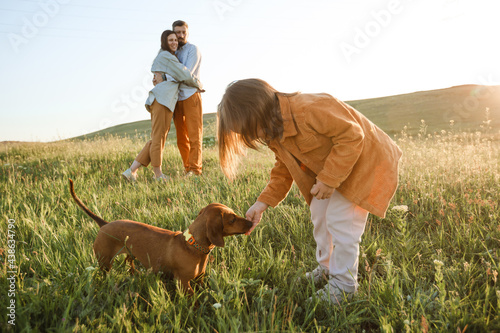 A hipster family walks in a summer field.