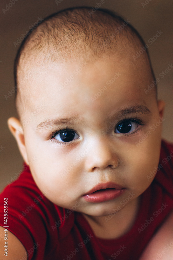 Portrait of cute baby close-up. Sweet little infant looks to camera. Bald baby with brown eyes and long lashes Portrait of cute baby close-up. Sweet little infant looks to camera. Bald baby with brown eyes and long lashes